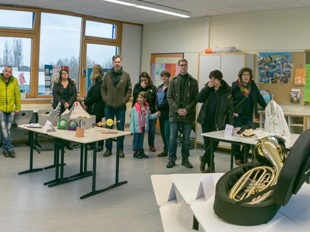 Besucher stehen in einem Raum mit ausgelegten Blechblasinstrumenten.